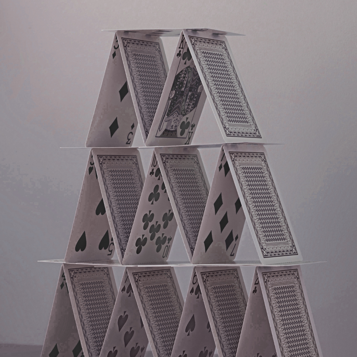 A tall black and white house of cards built from playing cards stacked in triangular layers.