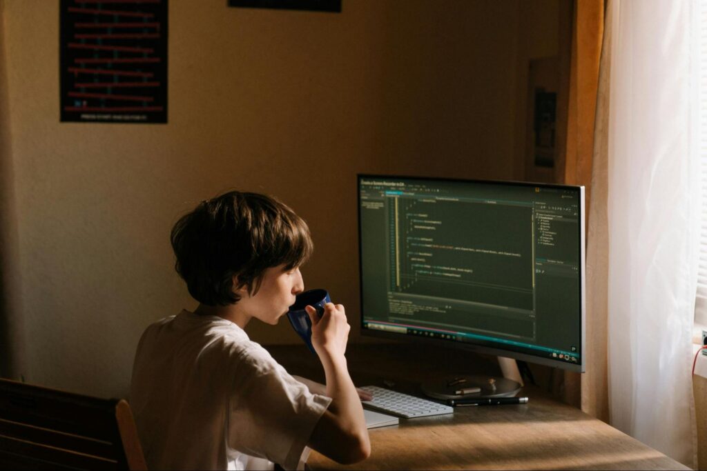 Image of a developer sitting at her desk sipping a coffee and mulling over a decision.