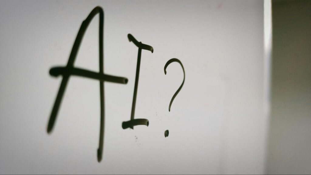 'AI?' written out on a whiteboard. These words supplement the visual appeal for our topic "When AI Isn’t the Answer"