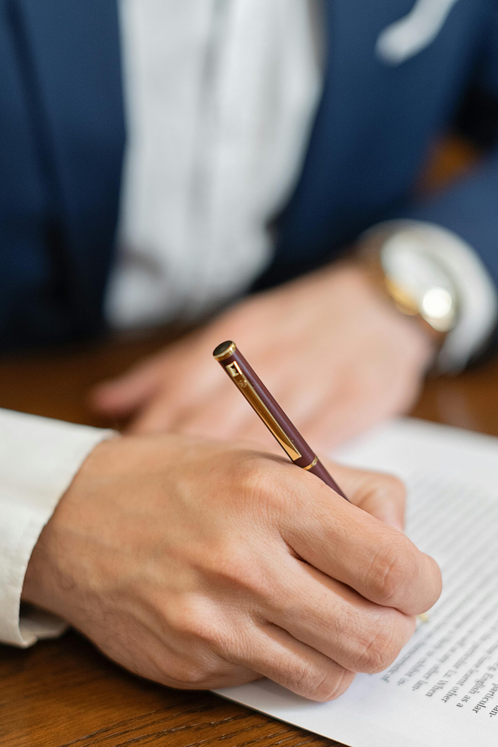 Close-up of a person writing on a document with a pen, representing formal decision-making, documentation, or approval.