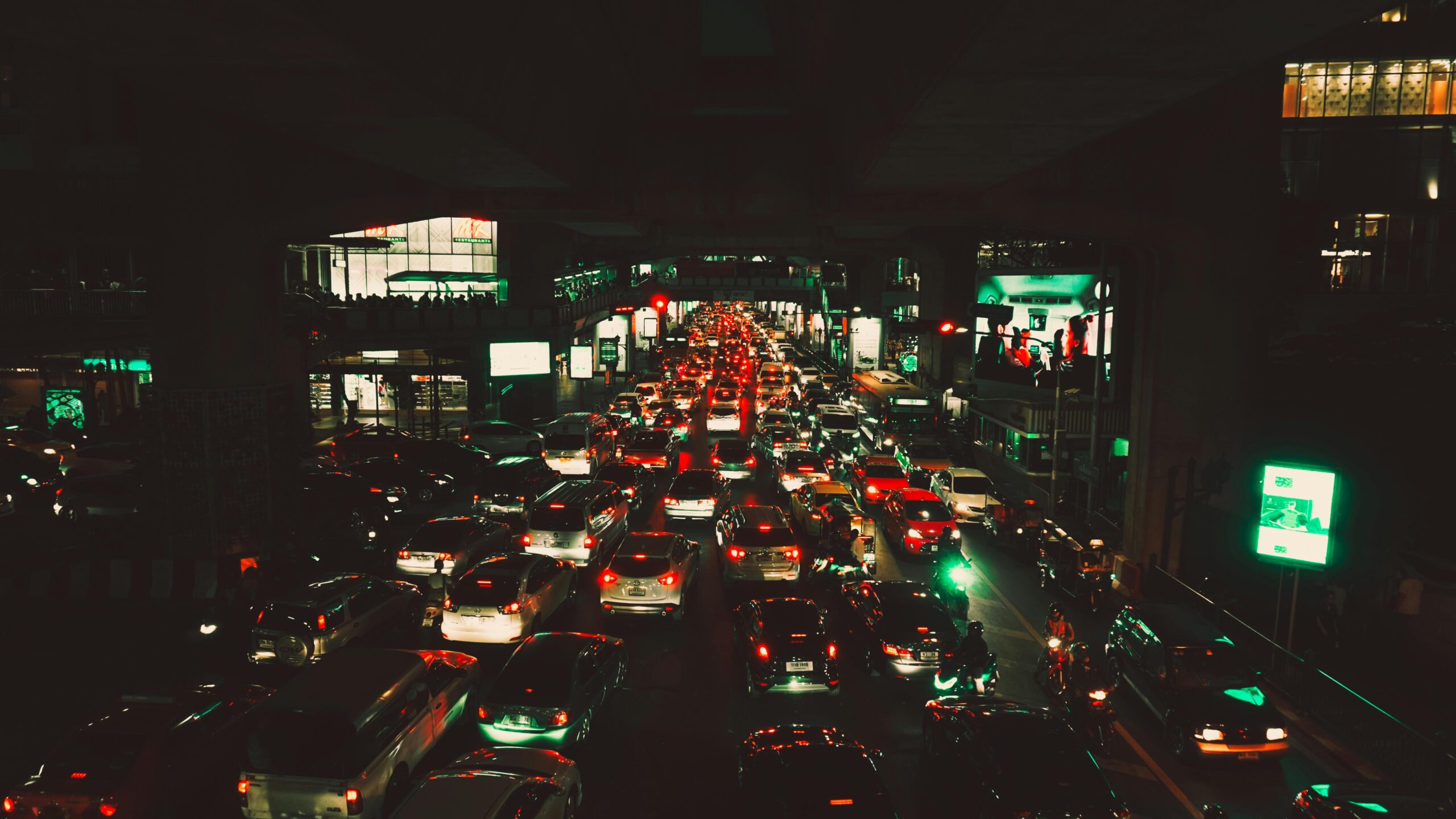 Heavy traffic congestion at night with tightly packed cars and glowing brake lights, representing bottlenecks, slowed movement, and system overload.
